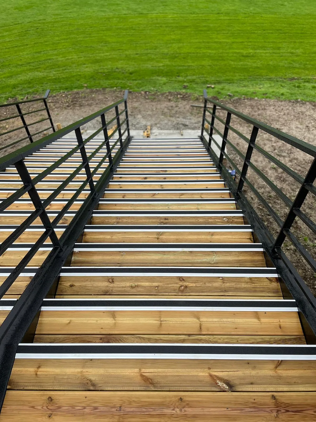 Vue d'ensemble de la passerelle métallique en cours d'installation avec garde-corps tubulaire et caillebotis