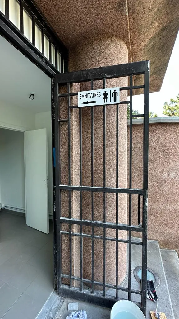 Grille métallique de sécurité noire avec signalétique sanitaires, menuiserie métallique sur mesure
