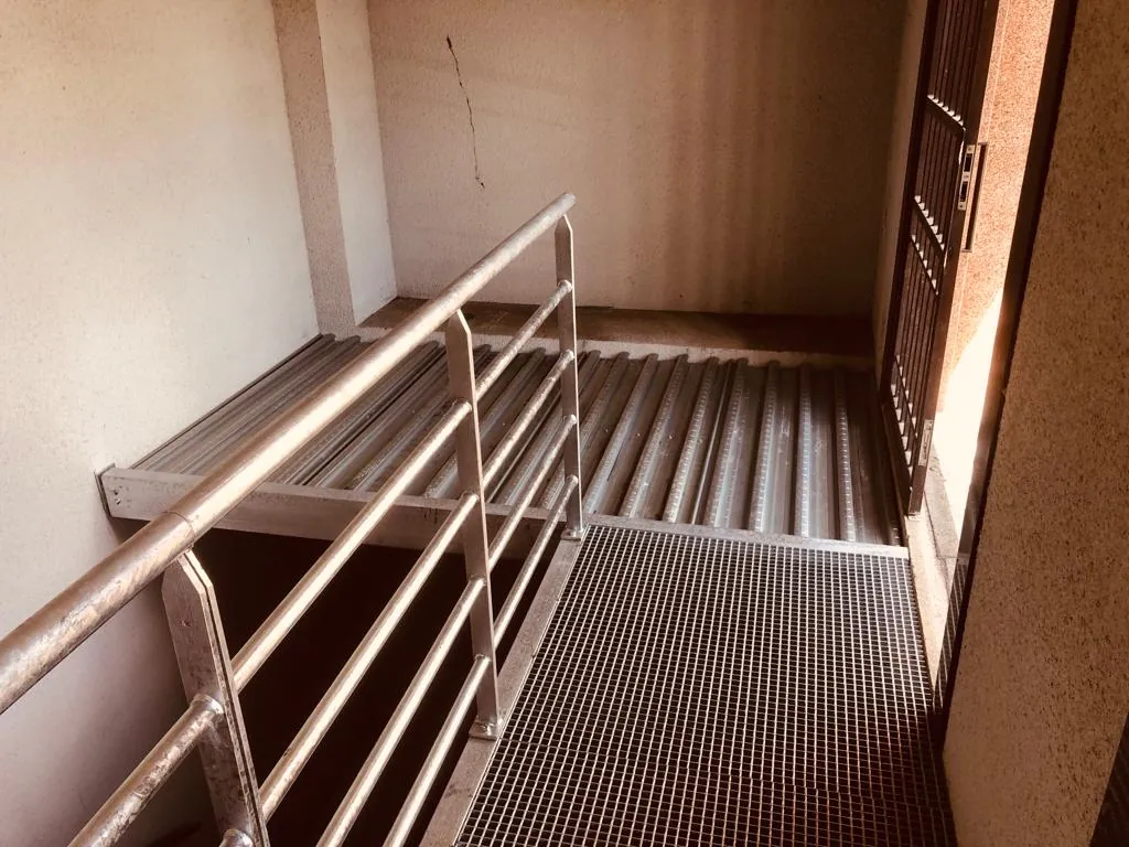 Passerelle métallique extérieure avec garde-corps tubulaire, plancher nervuré et caillebotis d'accès