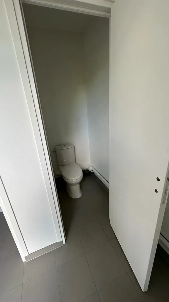 Cabine WC individuelle avec cuvette et réservoir installés, carrelage gris au sol, travaux de plomberie neuve