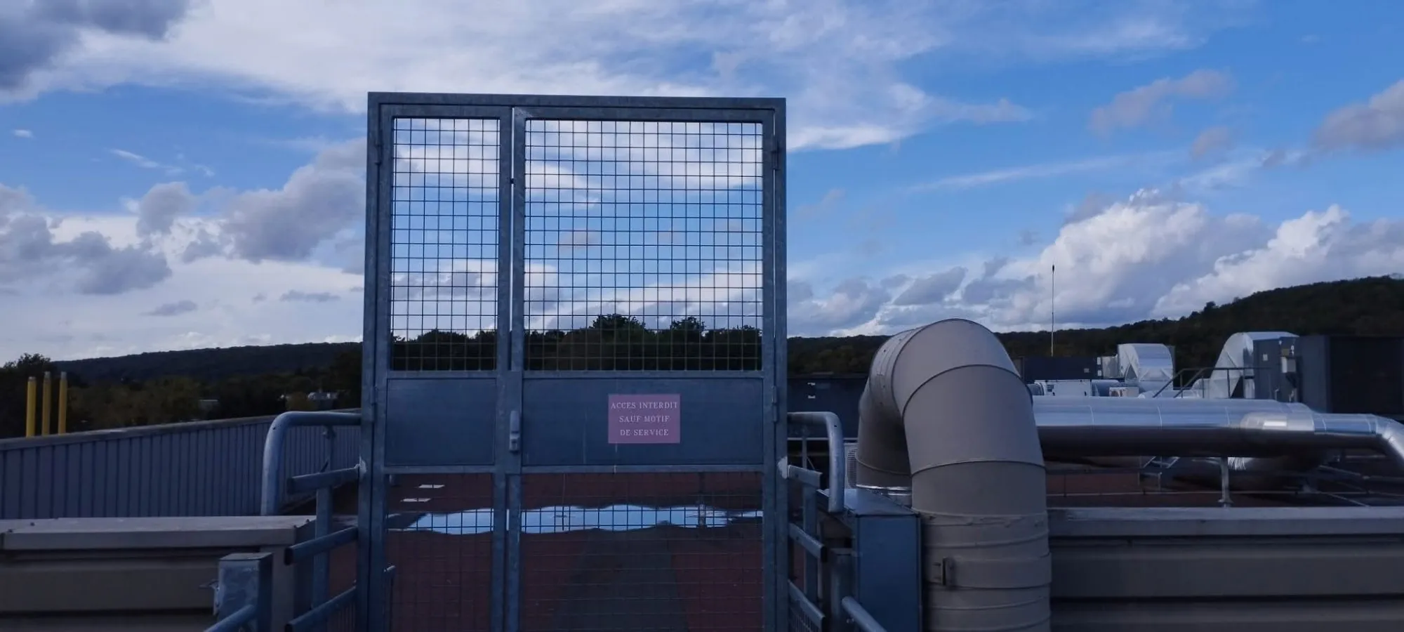 Portail métallique grillagé sur toiture avec panneau accès interdit - Sécurisation zone technique