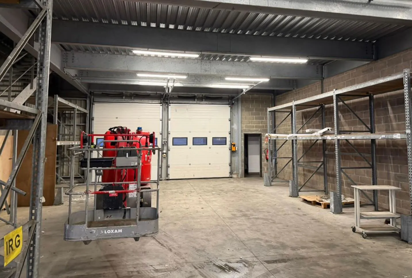 Rénovation hangar après - Local technique aménagé avec porte sectionnelle et rangements métalliques