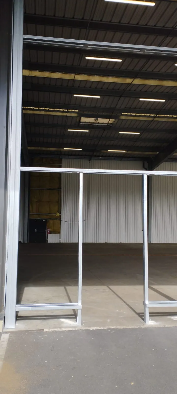 Intérieur d'un entrepôt industriel avec ossature aluminium en cours de pose — travaux menuiserie