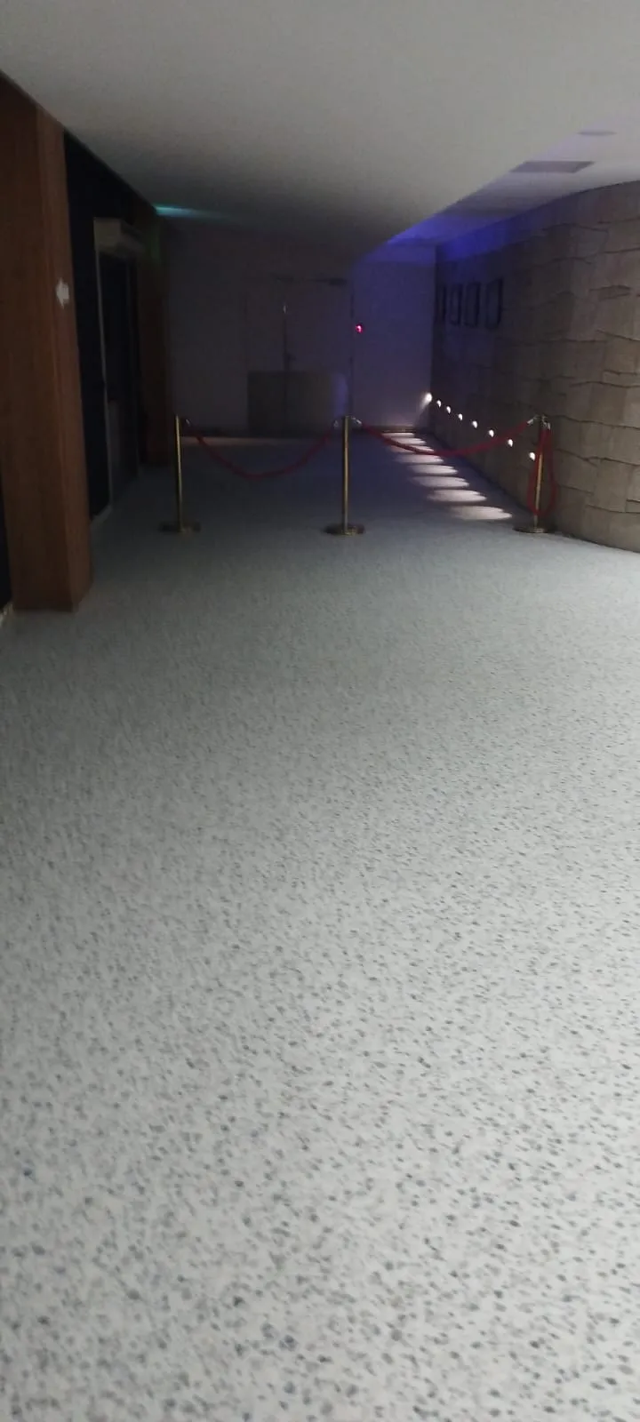 Couloir intérieur rénové avec sol en résine claire et cordon de sécurité doré — régie événementielle