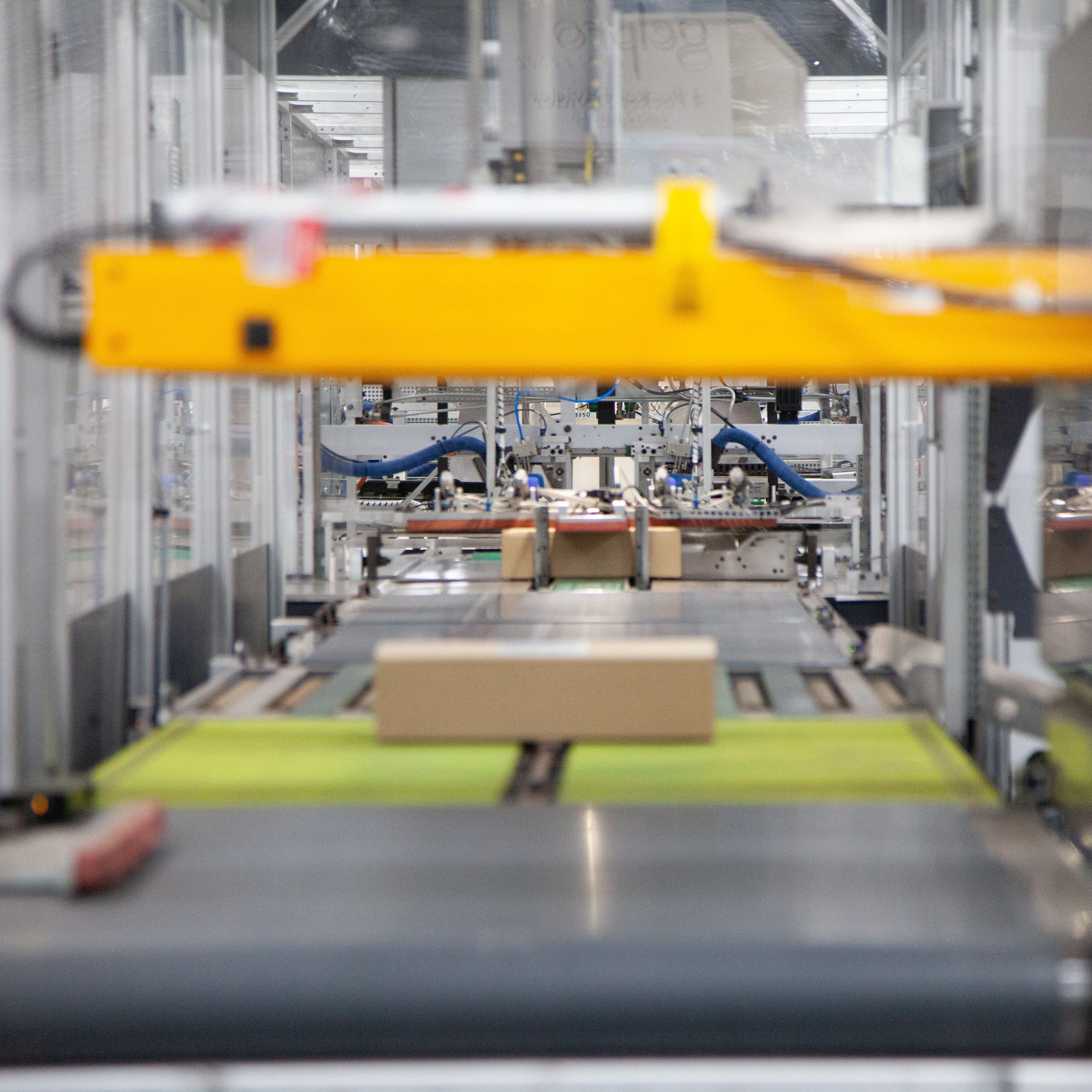 Packages moving on conveyor belts inside an automated sorting machine in a warehouse.