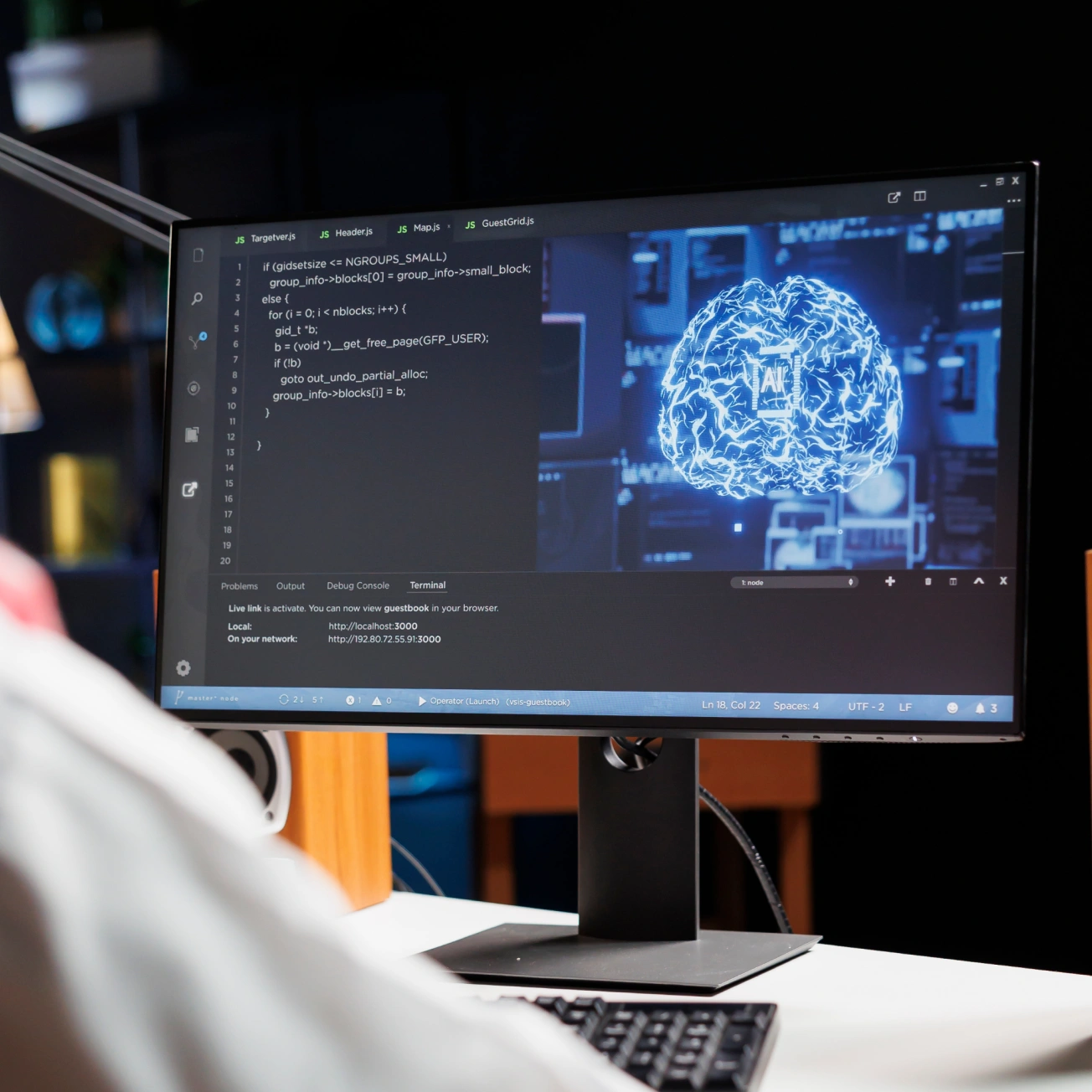 Computer monitor displaying code on the left and a glowing digital brain graphic on the right.