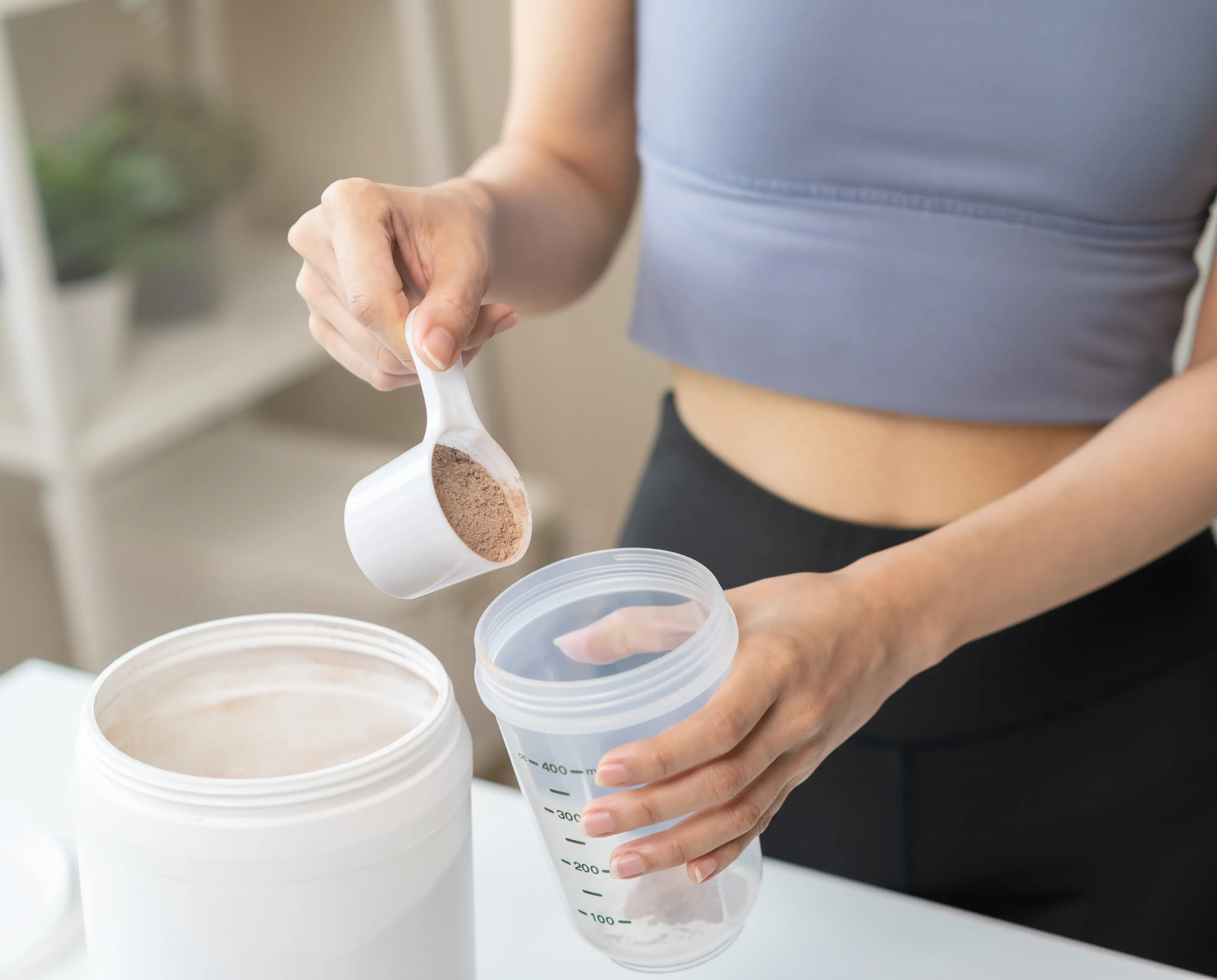The hand of a woman pouring whey protein powder