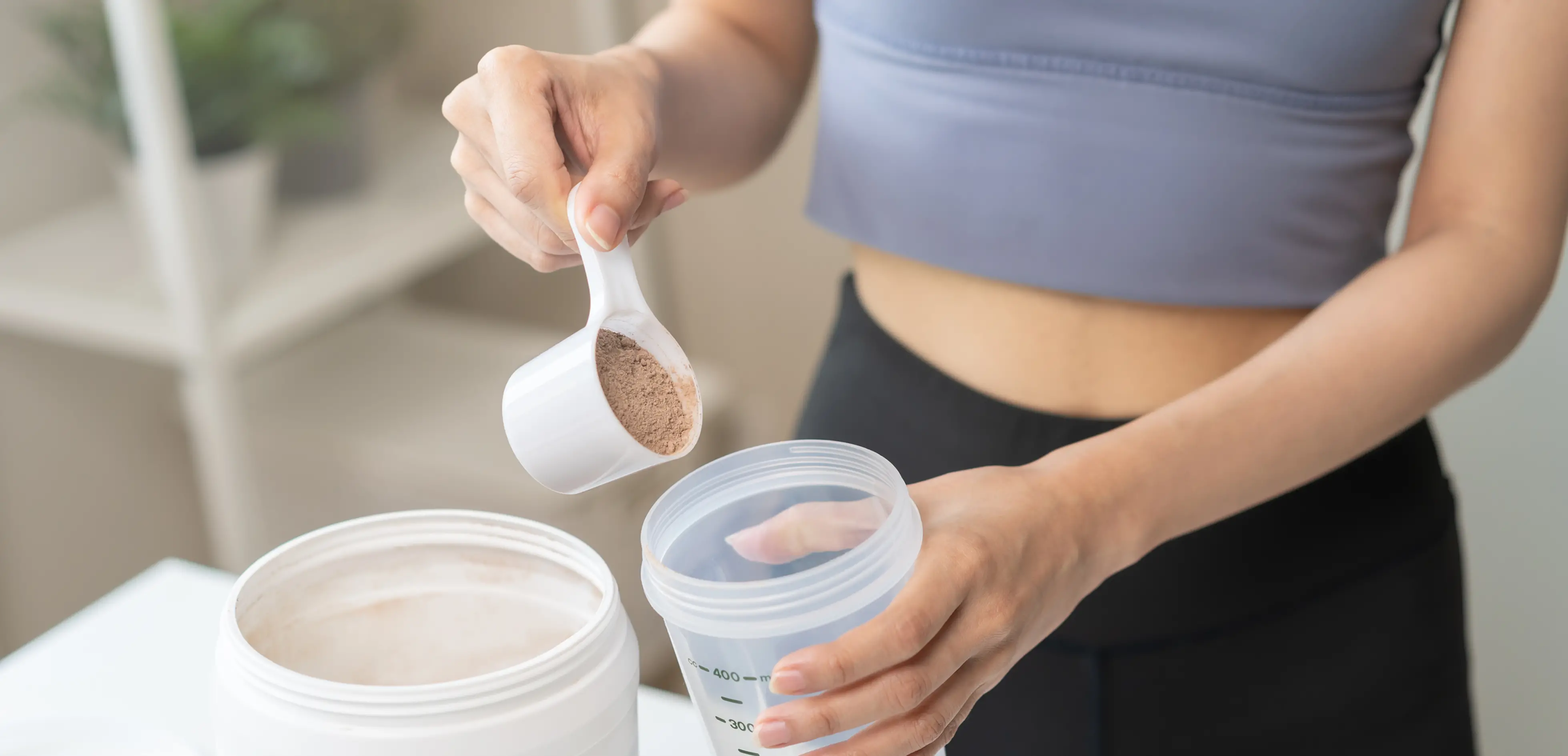 The hand of a woman pouring whey protein powder