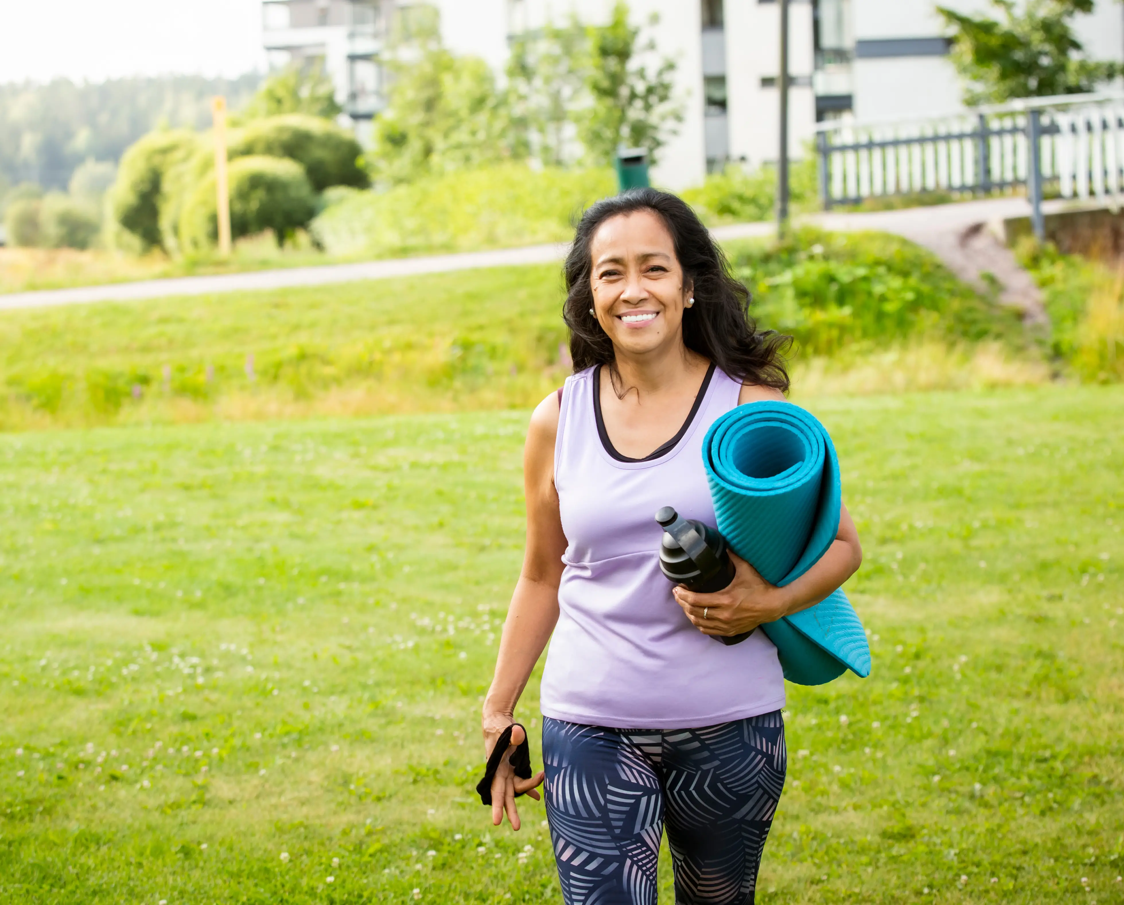 A woman walking with a yoga mat