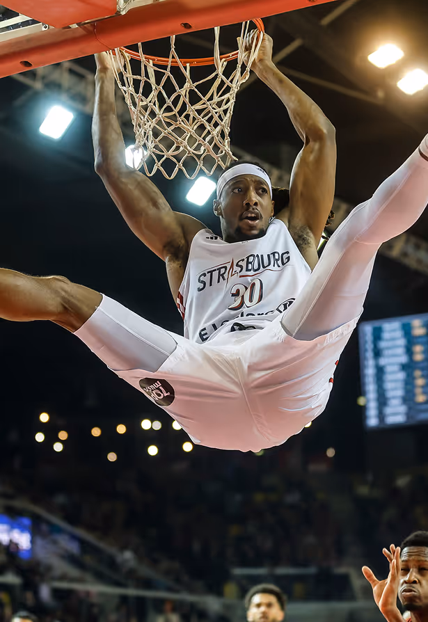 Groupe de cinq personnes courant sur un sentier près d'un arbre au bord d'un plan d'eau, avec de la fumée en arrière-plan.