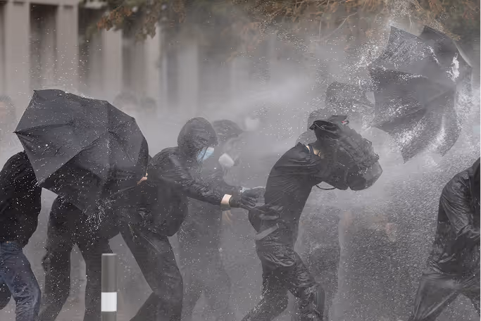 Homme chantant intensément dans un micro avec un tatouage de boussole sur le bras et un écouteur intra-auriculaire.