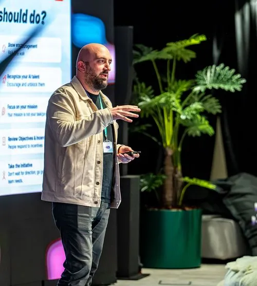 MLOps speaker gesturing toward a screen listing AI deployment strategies like focus on objectives