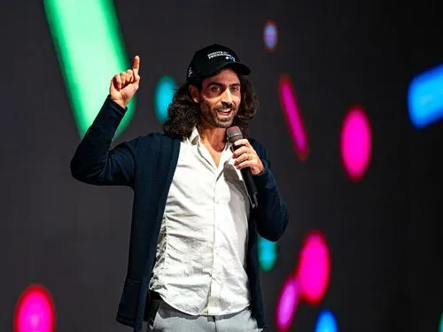 MLOps conference speaker holding a microphone and gesturing on a colorful stage
