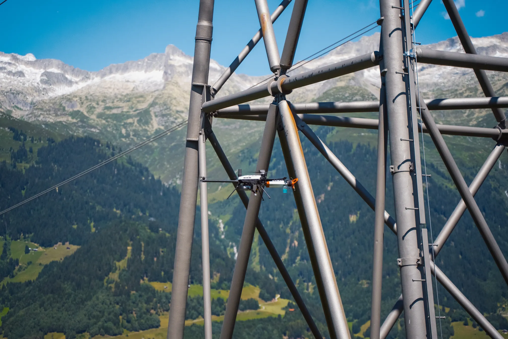 Small inspection robot performing contact-based measurement on a high-voltage transmission tower in the Alps