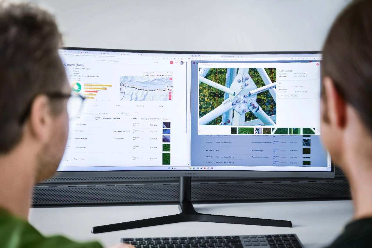 Two analysts reviewing tower inspection data and imagery on dual monitors