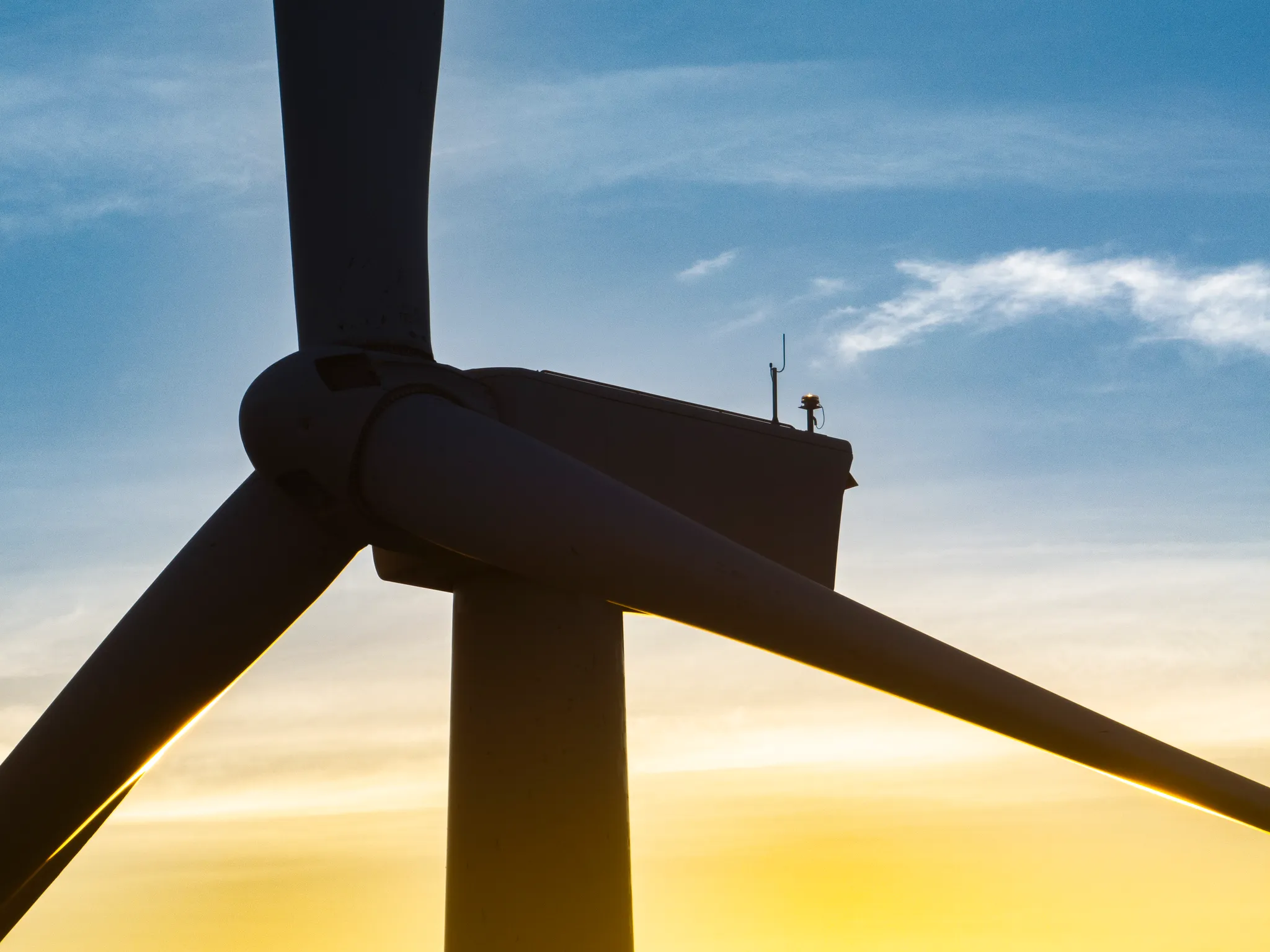 Close-up of a wind turbine rotor silhouetted against the sky at sunset