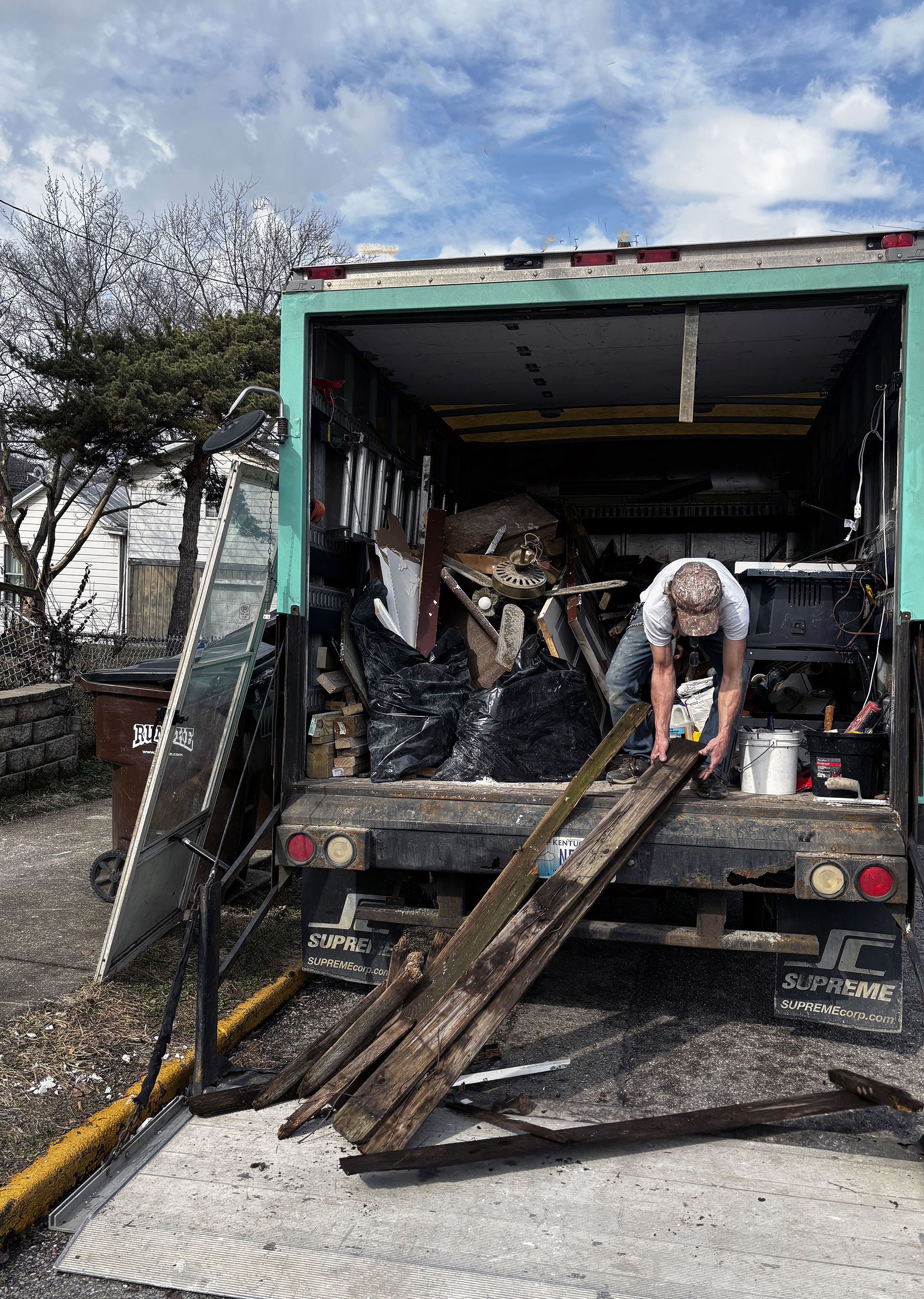 Crew loading debris and wood into junk removal truck for residential cleanout