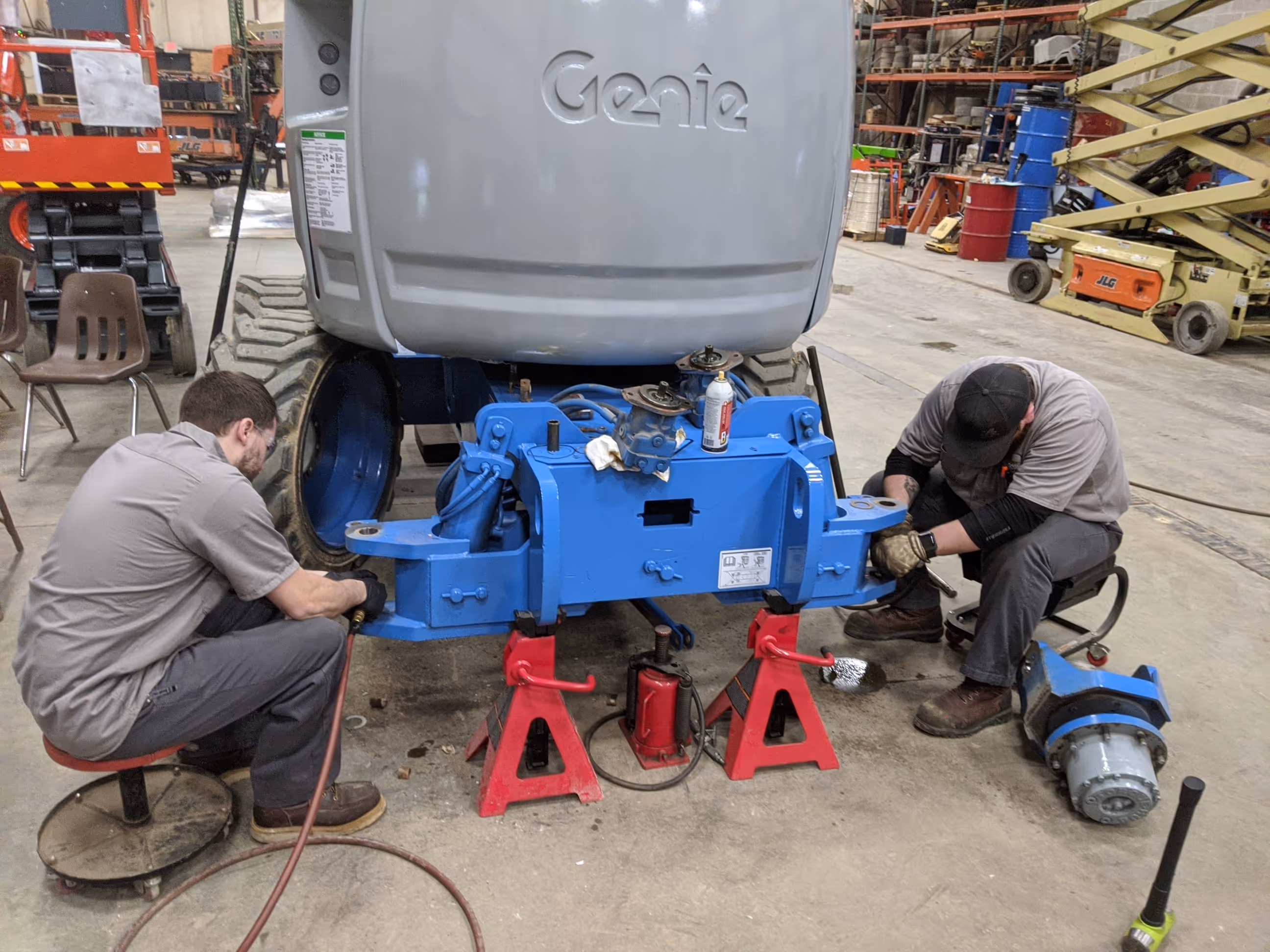 two technicians looking under and fixing a Genie lift
