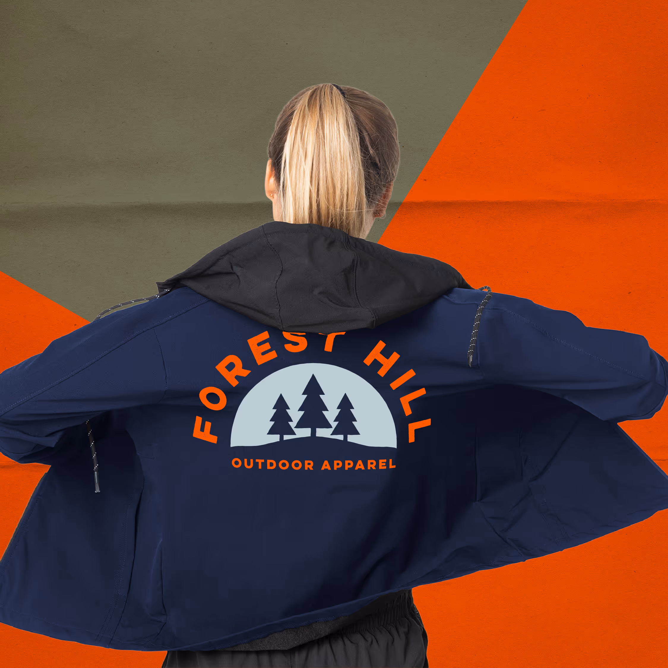 Person with blonde ponytail wearing a navy jacket with Forest Hill Outdoor Apparel logo featuring three pine trees on the back.
