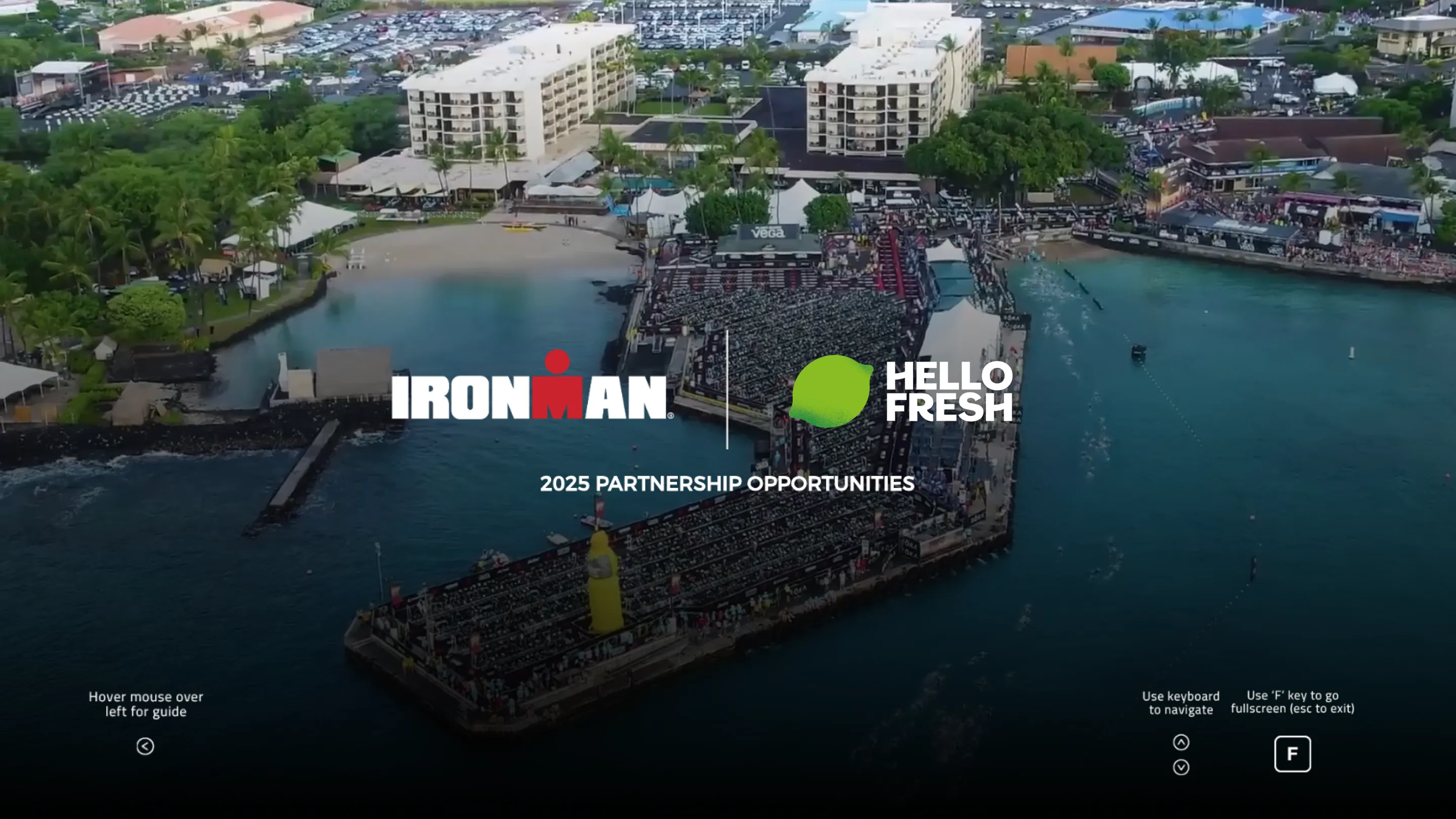 Aerial view of a waterfront triathlon event setup with Ironman and HelloFresh logos and text '2025 Partnership Opportunities' over the water and seating area.
