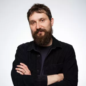 Mechanic in black gloves inspecting and repairing a car engine in a workshop.