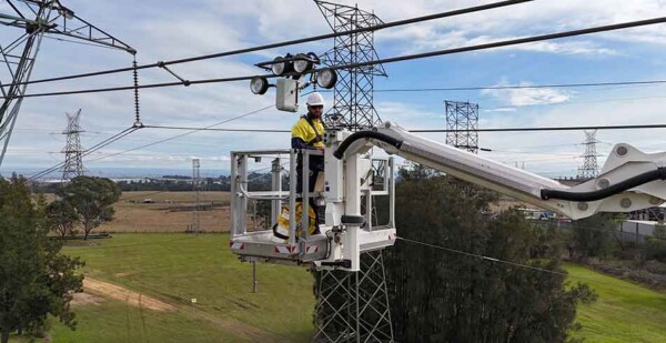 The Gorilla Mk1 robotic puller on high-voltage transmission line with Transgrid worker in crane bucket underneath