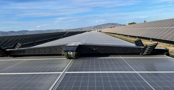 Robot cleaning solar panels with mountains in the background
