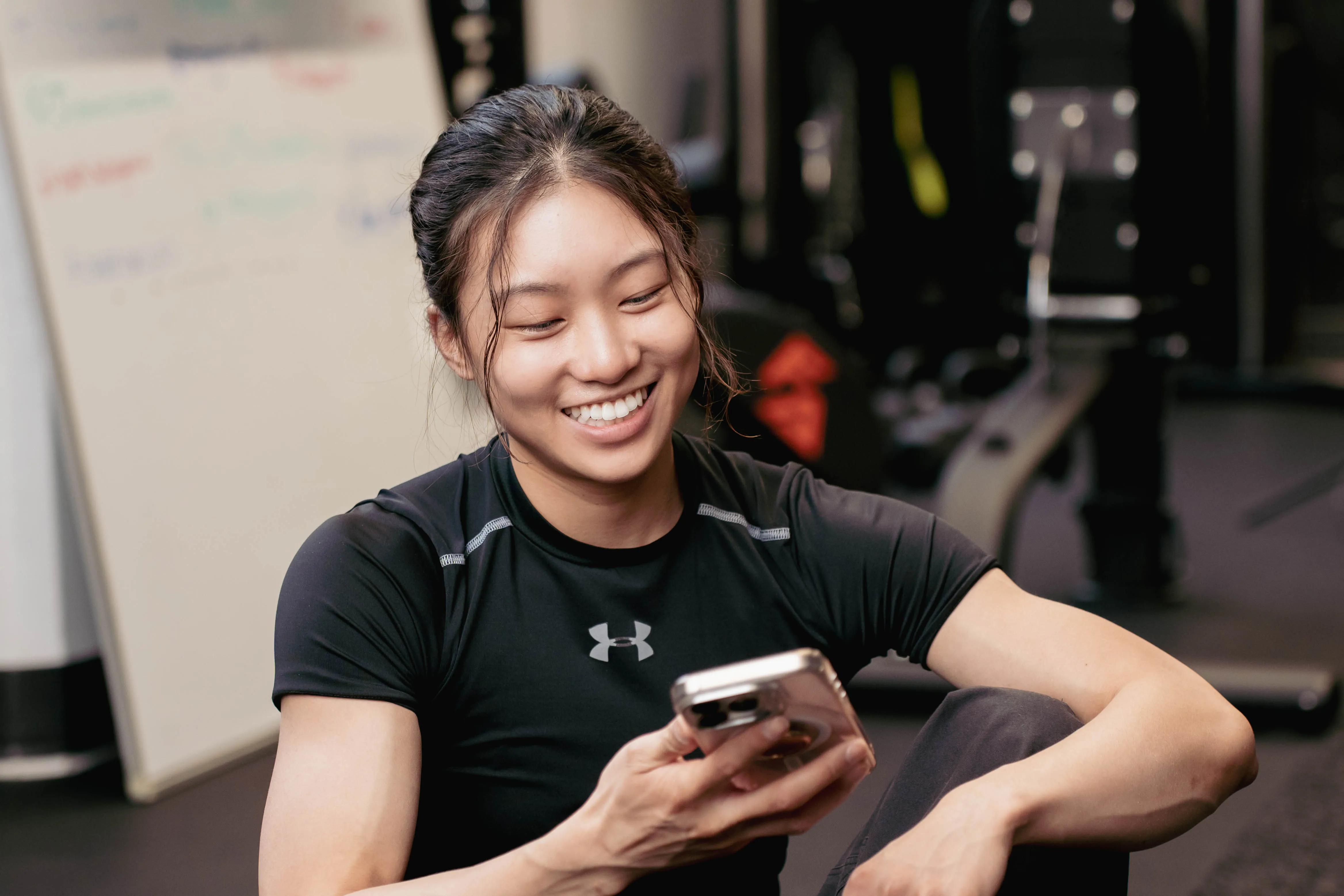 A personal trainer smiling while holding her phone.