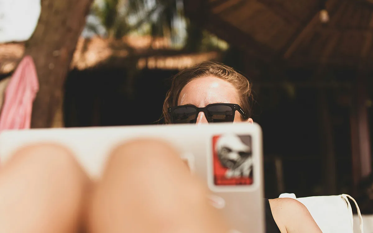 A woman sitting and looking at her laptop while on holiday