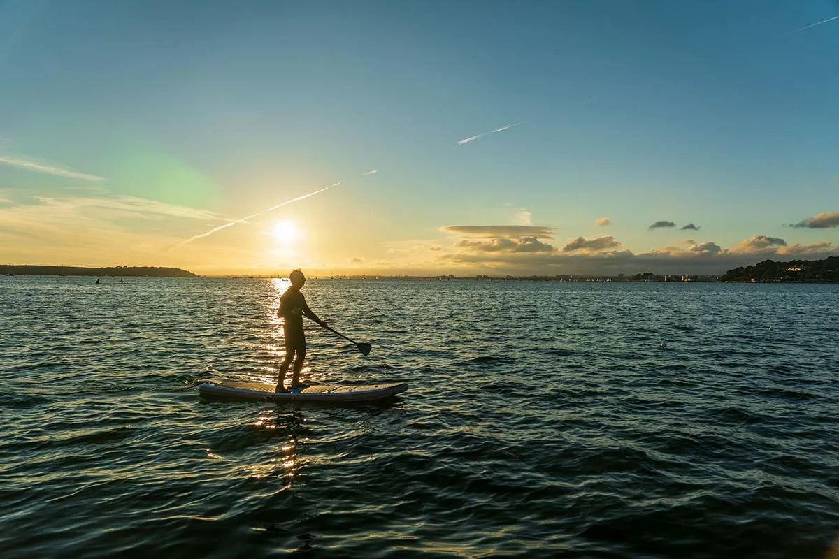 A man on a paddle board during a seaside sunset