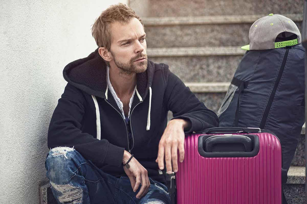 A man sitting on some steps with a suitcase