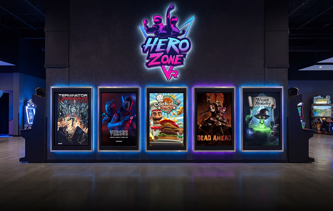 Hero Zone VR arcade wall with illuminated posters for games Terminator Uprising, Versus, Cook’d Up, Dead Ahead, and Wizard Academy.