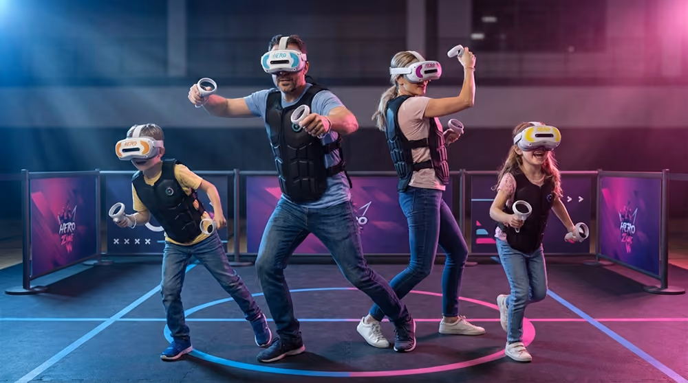 Family of four playing in a virtual reality game zone wearing VR headsets and holding controllers.