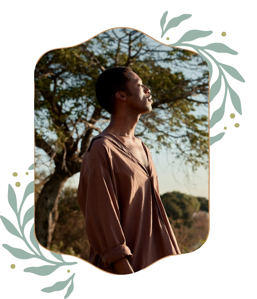 Profile of a young man with eyes closed, standing outdoors in natural light near a tree.