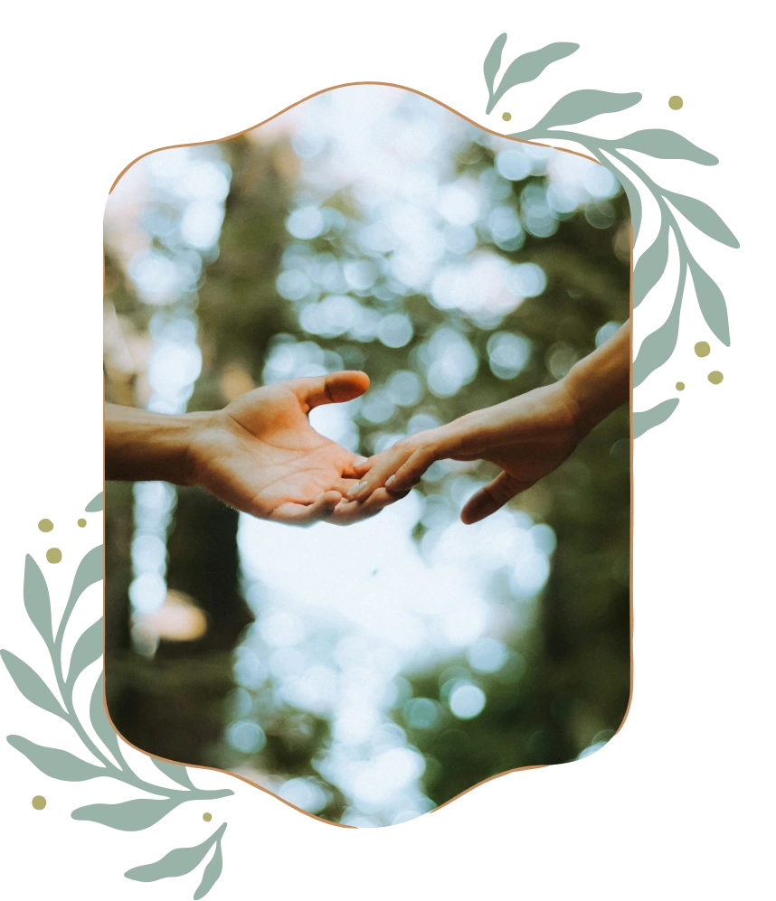 Two hands reaching out to touch with a blurred background of greenery and light.