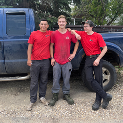 An image of the team at Badger Landscaping, standing in front of their truck, laughing in Edmonton, Alberta.