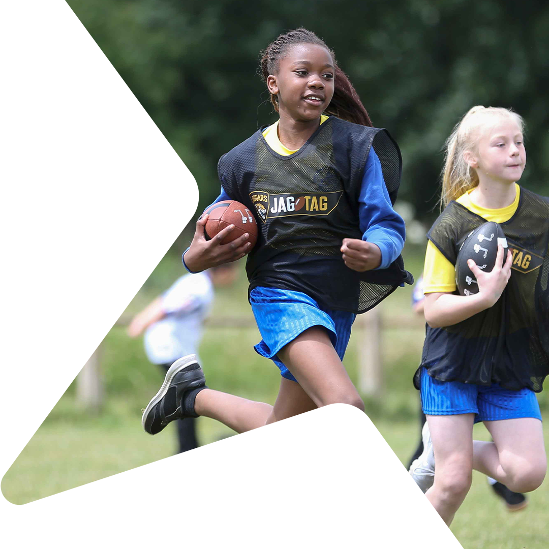 Two girls running with American footballs.