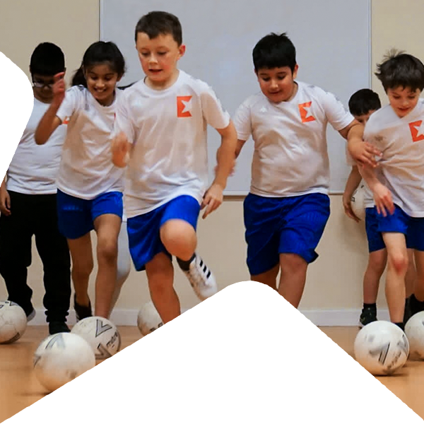 A group of kids running towards camera kicking footballs.