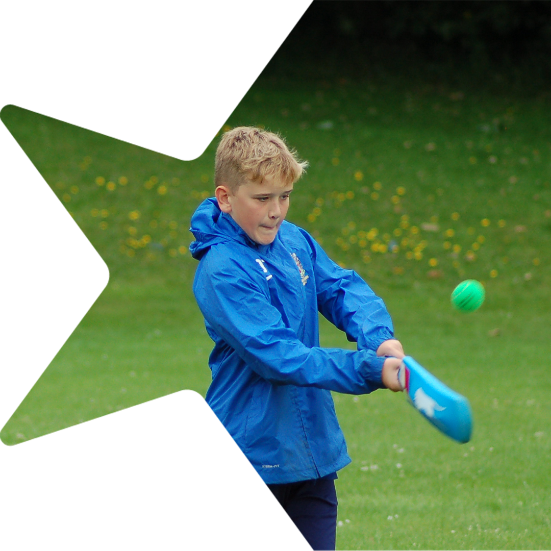 Boy swinging cricket bat at a ball.