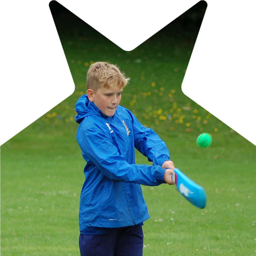 Boy swinging cricket bat at a ball.