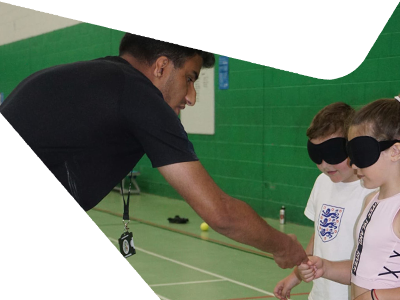 Two children with a sports coach playing football.