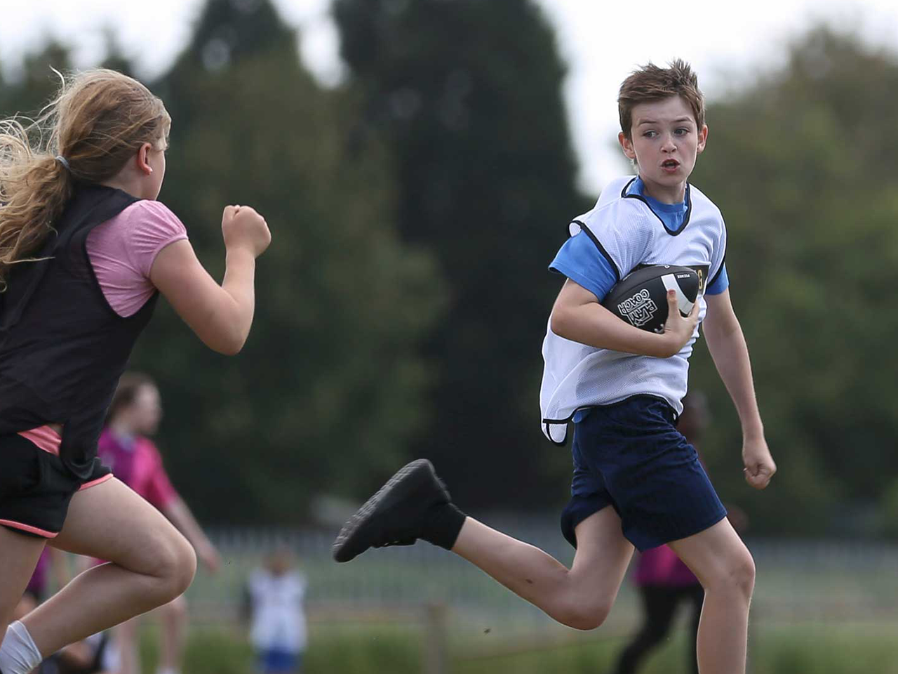 A boy running away with a American football.