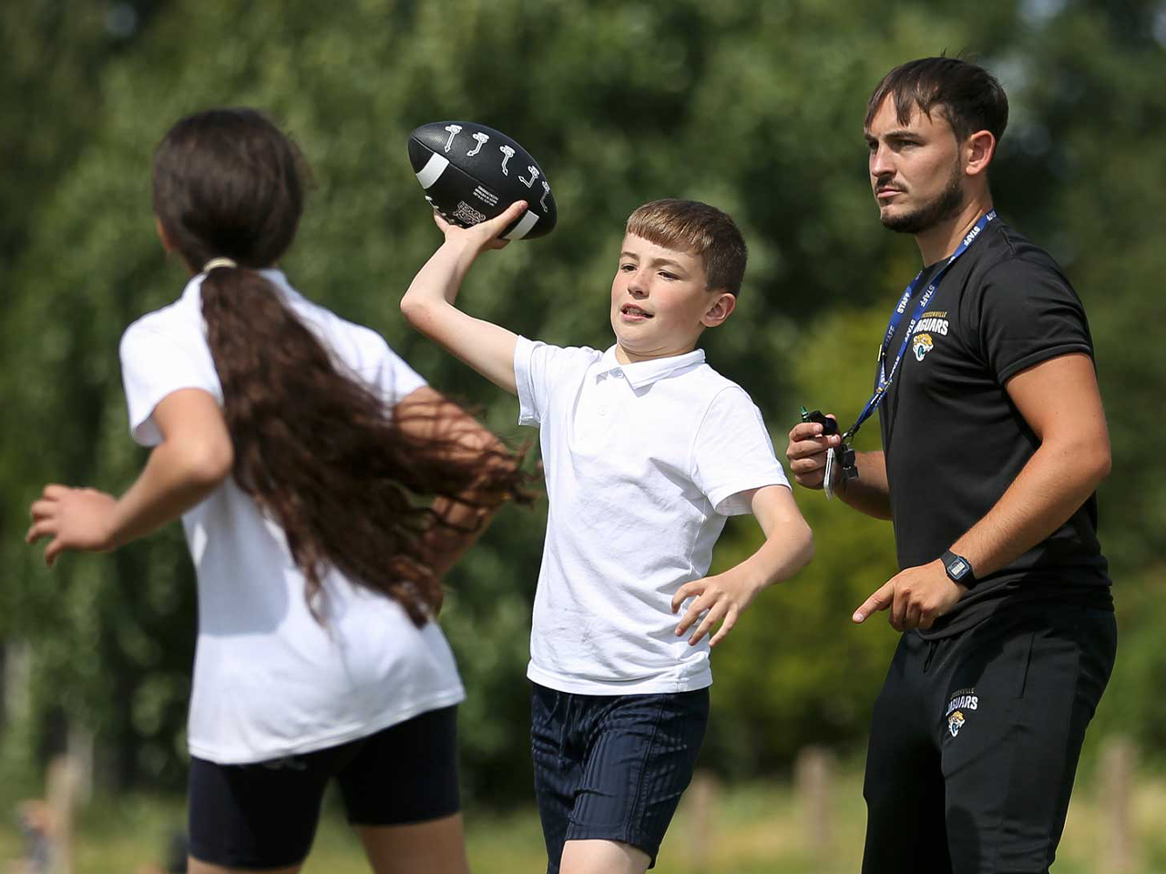 A boy throwing an American football in a game.