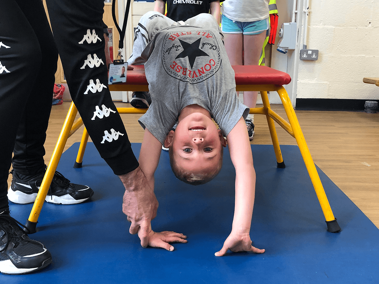 A coach teaching a child how to perform a backwards handspring.