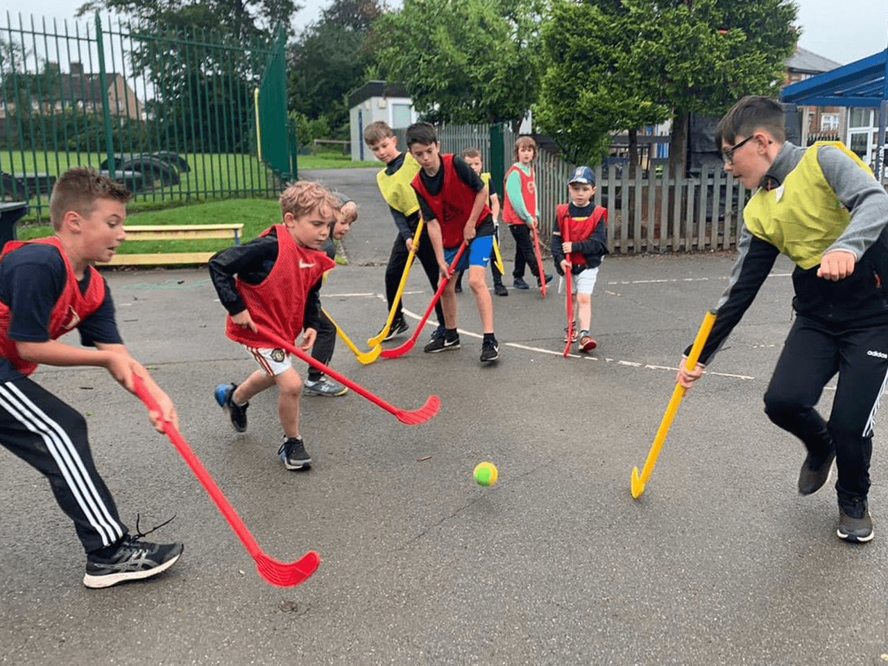 A group of children playing a hockey match in a playground.