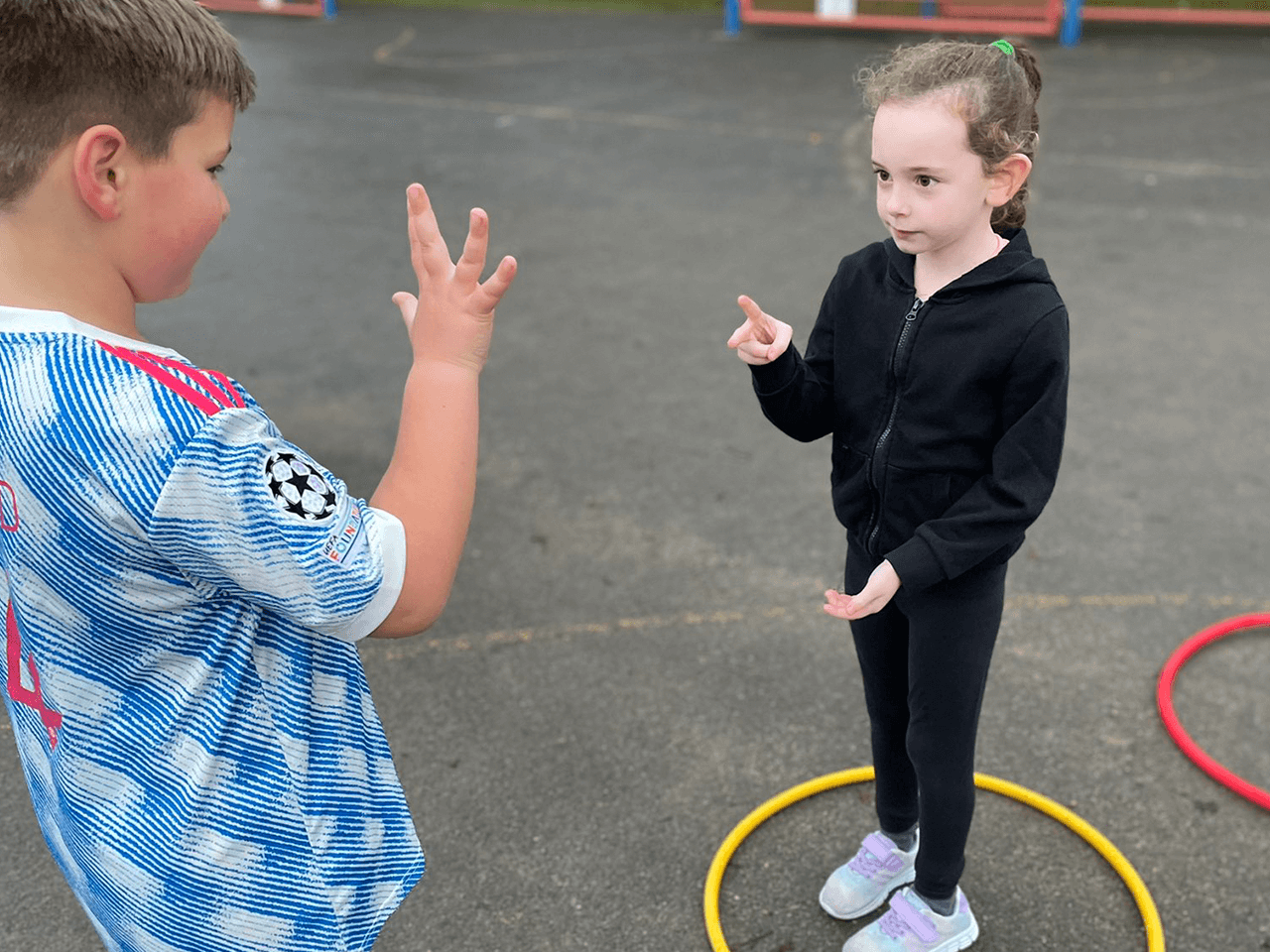 A boy and a girl playing a counting game in the school playground.