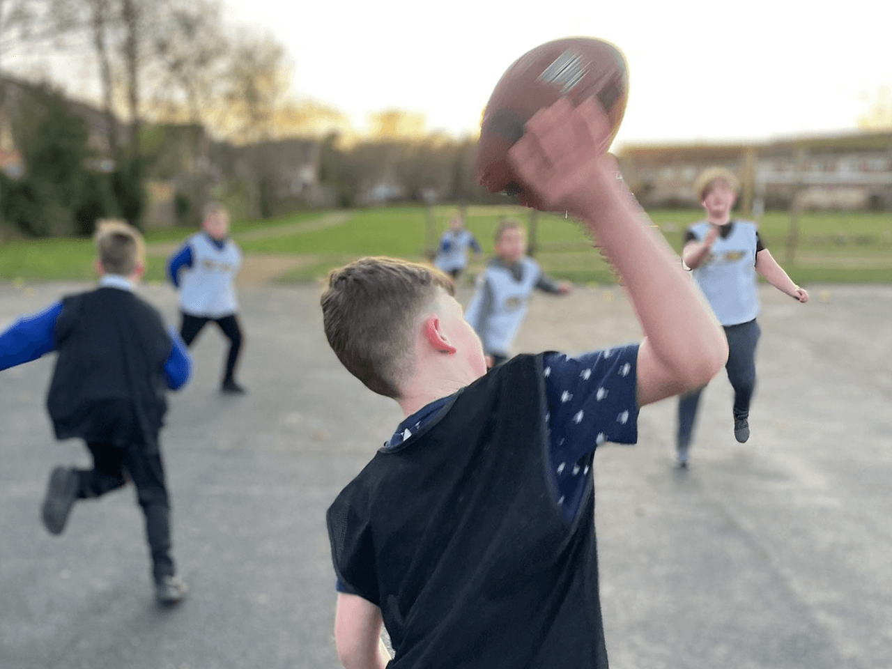 A boy throwing an American Football to his team mates.