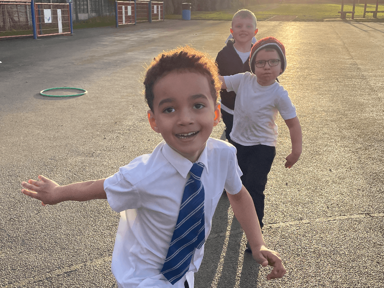 Three school boys running around in the playground.
