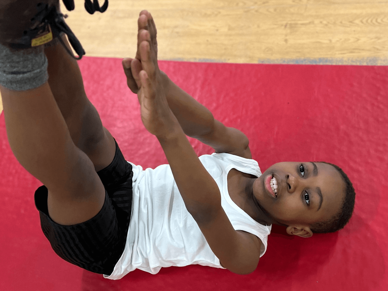 A young boy led on his back with feet in the air reaching his toes.