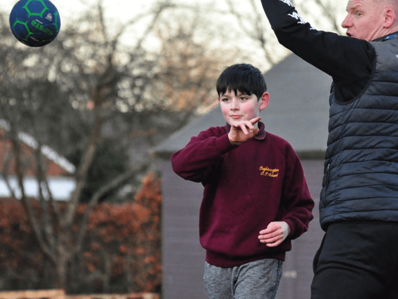 A coach teaching a child how to throw a ball.